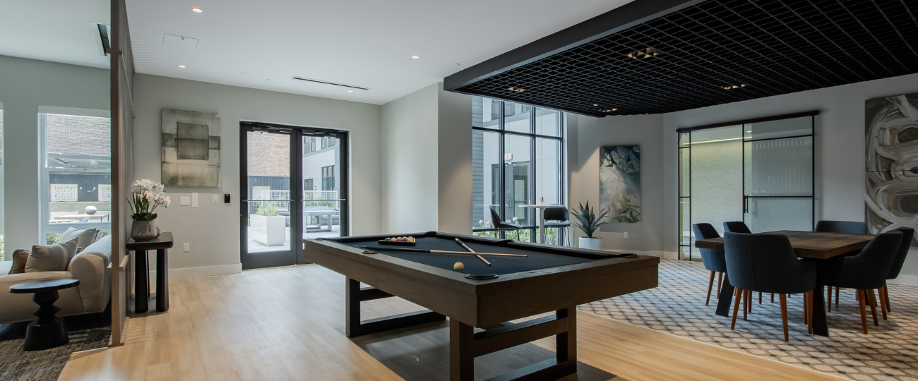 Modern resident clubroom at The Rail at Bound Brook with pool table, lounge seating, and direct courtyard access – luxury apartment amenities in downtown Bound Brook, NJ.